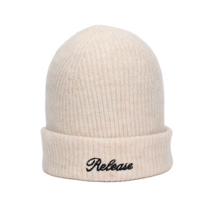 Detail of cream rib-knit beanie showing soft texture and black Release cursive embroidery