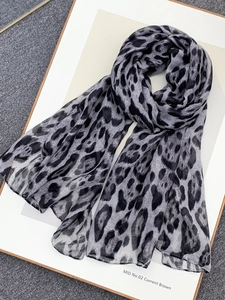 Detail view of leopard print voile scarf in grey and black tones on flat lay surface