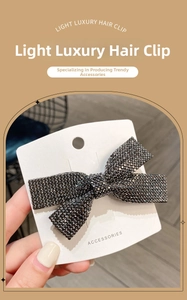 Macro detail of luxury rhinestone bow hair clip with black crystal pavé on metal base