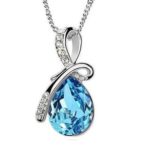 Macro detail of a silver pendant with a teardrop blue crystal and small clear gemstones