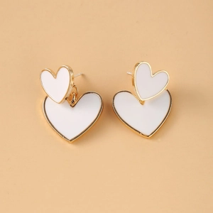 Close-up of elegant double heart stud earrings featuring a gold base and white enamel finish