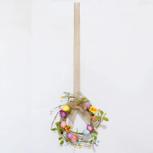 Detail of Easter wreath featuring colorful faux eggs and daisies on a rustic branch base
