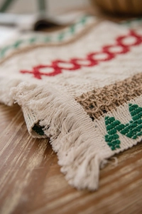 Macro detail of Christmas table runner featuring jute weave and festive tassels