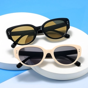Retro cat-eye sunglasses with black and beige frames on a minimalist pedestal