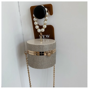 Detail of cylindrical clutch bag with sparkling silver rhinestones and pearl handle