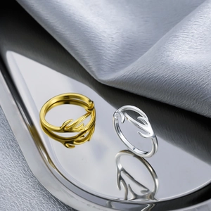 Detailed view of silver and gold antler rings on a reflective metallic tray with silk