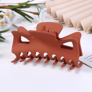 Close-up of matte caramel brown hair claw clip with elegant floral background