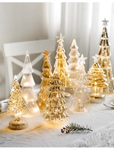 Close-up of assorted glass Christmas trees with warm LED lights and assorted finishes