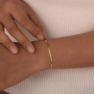 Close-up of a minimalist gold herringbone snake chain bracelet on a model's wrist