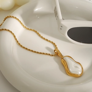 Golden twist chain necklace with white baroque pearl pendant in a ceramic dish