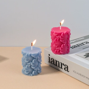 Nahaufnahme der floralen Reliefstruktur auf zylindrischen Duftkerzen in Blau und Rosa