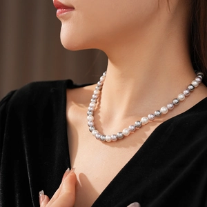 Detailed view of multi-color pearl necklace on neck featuring white, gray, and purple pearls