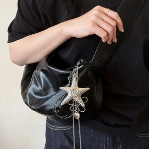 Detail of matte black crossbody bag featuring a large silver starfish metal pendant and chain