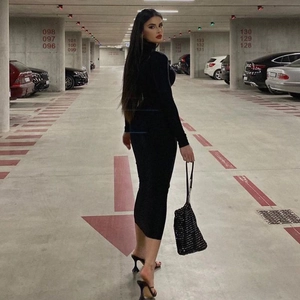 Chic back view of a black slim-fit high-neck long-sleeve dress and matching beaded handbag