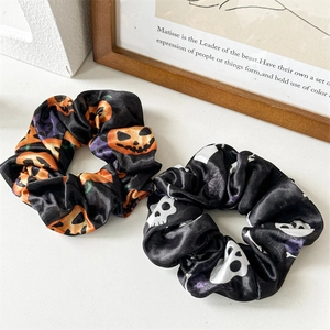 Detail of Halloween hair scrunchies featuring orange pumpkin and white skull prints on satin