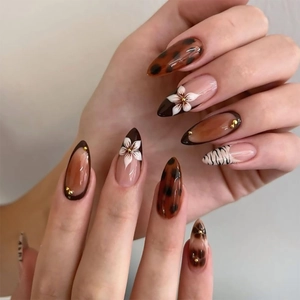 Detail of almond nails featuring leopard print, 3D white flowers and French brown tips