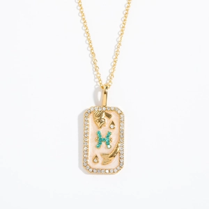 Detail of gold Pisces necklace pendant with white enamel and turquoise stones