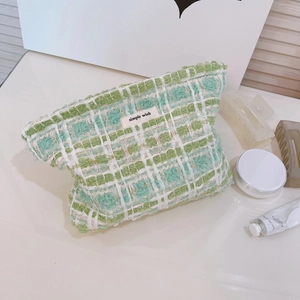 Green and white tweed cosmetic bag with Simple Wish label on a white tabletop