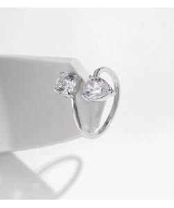 Macro shot of silver ring with round and pear-shaped zircon stones on white background
