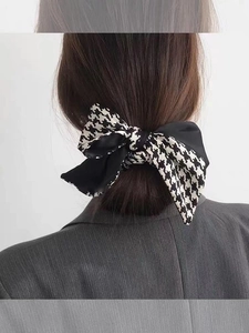 Detail of checkered bowtie hair scrunchie styled on a low ponytail for women