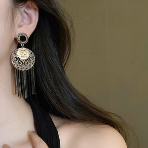 Détail des boucles d'oreilles vintage en or avec élégantes longues chaînes à glands noirs