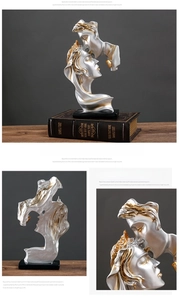Detail view of silver and gold resin couple kissing sculpture with black base