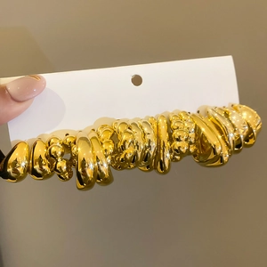 Close-up of assorted gold pleated stud earrings on card with a high-polished metallic finish