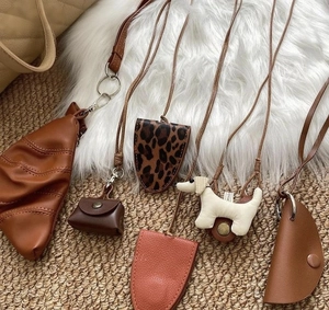 Detailed flat lay of leather puppy charms and mini pouch necklaces in assorted colors