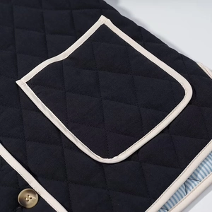 Detailed close-up of navy quilted diamond texture with cream trim and striped lining