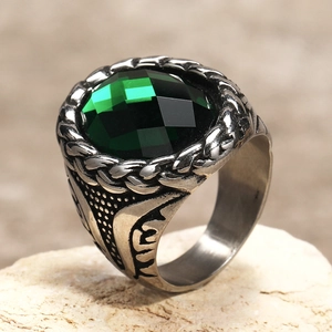 Macro detail of men's vintage steel ring with green faceted gem and woven patterns