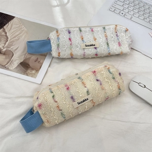 Detail of floral woven pencil bags in cream and apricot colors with portable handles