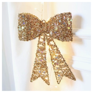 Close-up of golden sequined Christmas bow with warm LED fairy lights for holiday decor