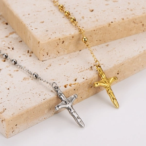 Detailed close-up of gold and silver stainless steel crucifix necklaces on stone stand
