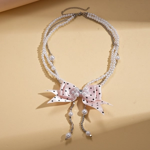 Elegant layered faux pearl necklace with pink polka dot ribbon bow and sparkling crystal center