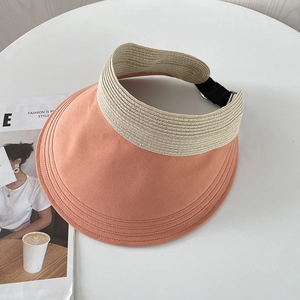 Detail of orange-pink sun visor hat with adjustable strap on a white table background
