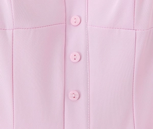 Dettaglio dell'abito rosa che mostra la trama in saia e tre bottoni coordinati