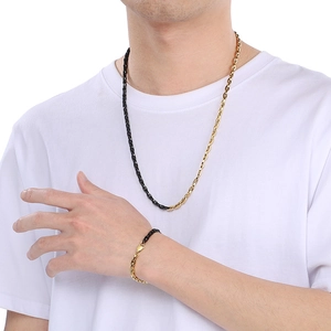 Detail of model wearing a two-tone black and gold stainless steel necklace and bracelet set