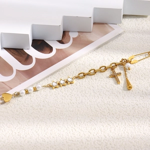 Close-up of gold cross pendant necklace with pearl and star charms on textured surface