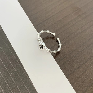 Detail of silver beaded ring with black stone cross charm on wooden background