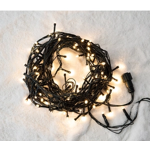 Detail of warm white LED Christmas fairy lights with power connector on snowy background