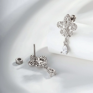 Silver iris earrings with drop shaped zircon on white silk background, elegant design