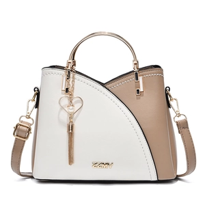 Color-block faux leather handbag with gold handle and heart tassel charm on white background