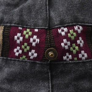 Close-up of ethnic jacquard ribbon and vintage metal rivet on dark grey cotton bucket hat