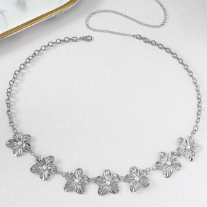 Detailed macro view of silver flower waist chain with delicate faux pearl centers