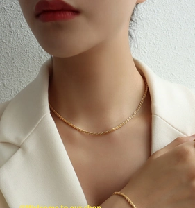 Close-up of a delicate gold minimalist chain necklace and bracelet set on a model in white
