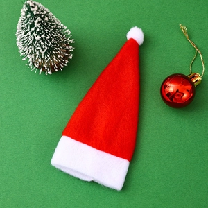 Close-up of a red and white mini plush Christmas hat on a green festive background