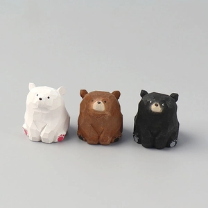 Three hand-carved wooden bear figurines in white, brown, and black with natural wood grain