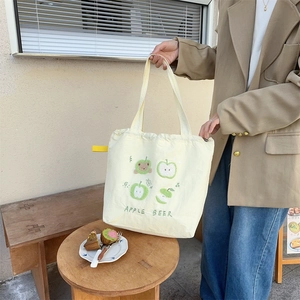 Close-up of cute bear and apple embroidery on a beige canvas tote shoulder bag