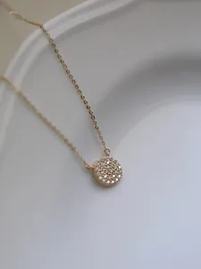Macro view of a 14k gold plated S925 sterling silver necklace with pavé round pendant