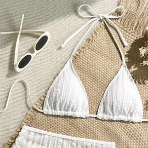 Flachbild des weißen strukturierten Bikinis mit Nackenbändern auf einer Strandmatte